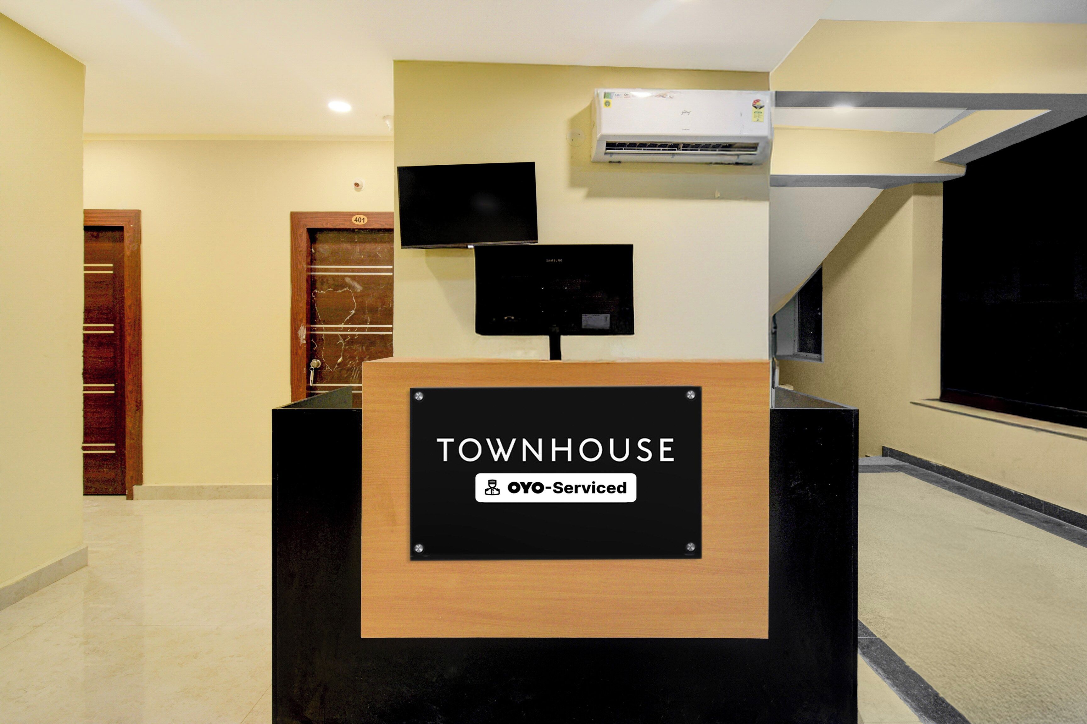 A reception desk with a sign reading 'TOWNHOUSE' and 'OYO-Serviced.'