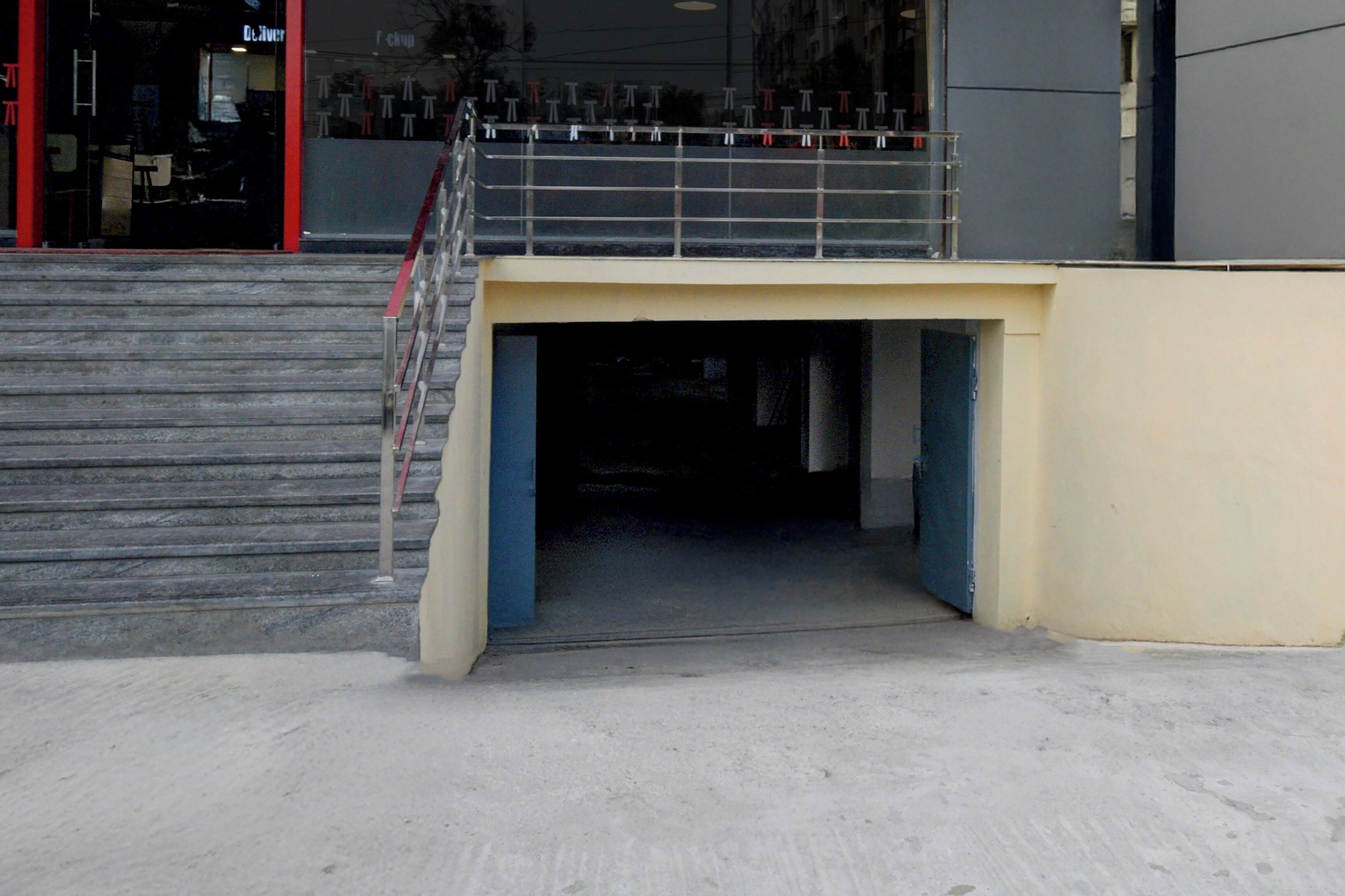 A staircase leading to a building entrance with a metal railing and a concrete platform.