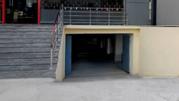 Una escalera conduce a la entrada de un edificio, con barandilla metálica y plataforma de concreto.