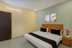 A hotel room with a bed, nightstand, and a wall-mounted light fixture. - Townhouse Oak NFC Crossway Hyderabad (Hyderabad)