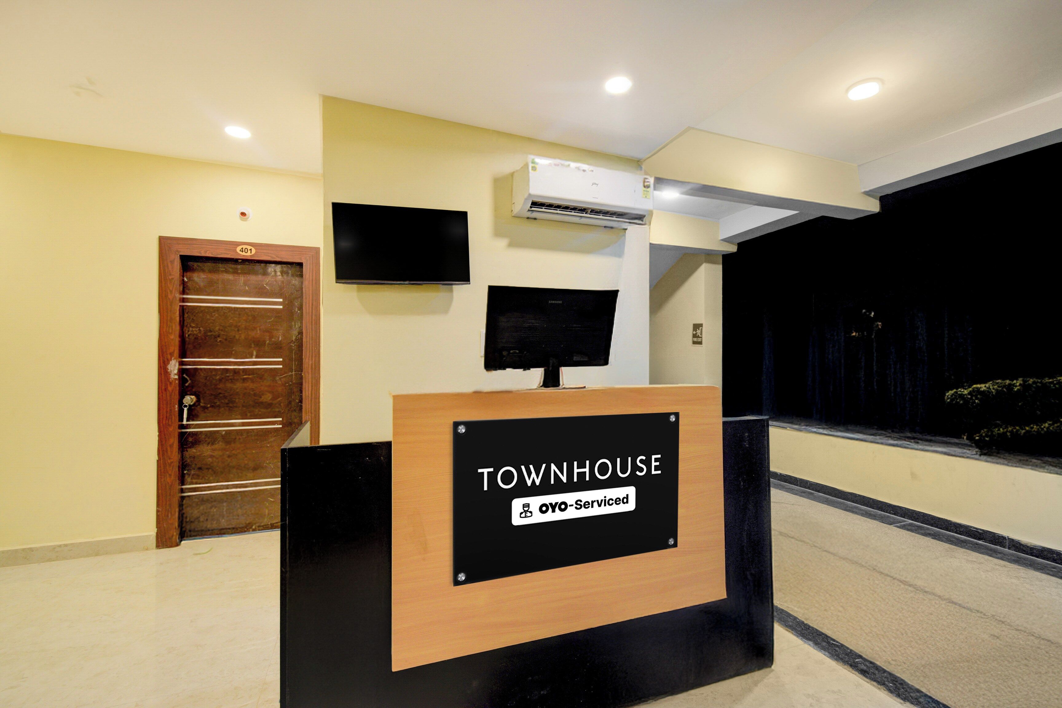 Ein Empfangsschalter mit einem Schild, auf dem 'TOWNHOUSE' und 'OYO-Serviced' steht.