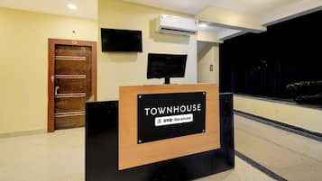 Ein Empfangsschalter mit einem Schild, auf dem 'TOWNHOUSE' und 'OYO-Serviced' steht.