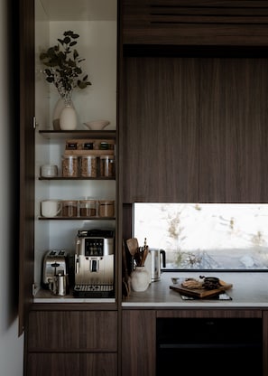 A kitchen with a coffee machine, jars, and a window view. - Te Anau Hilltop Hideaway - Luxury retreat perched above Fiordland (Te Anau)