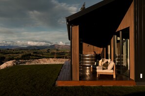 A modern building with a wooden exterior, a deck, a sauna, and a glass door leading to a seating area. - Te Anau Hilltop Hideaway - Luxury retreat perched above Fiordland (Te Anau)
