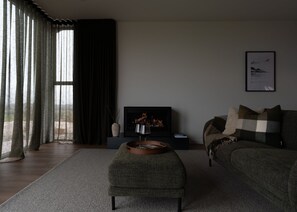 Un salon moderne avec une cheminée, un canapé, une table basse et un téléviseur.