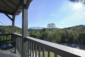 A wooden deck with a view of a forested landscape and distant mountains. - Bluff Mountain Vista • 4 Bed • 3 Bath • Stunning Views (Sevierville)
