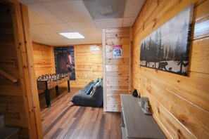 A room with wooden walls, a foosball table, a sofa, and a painting of a bear. - Bluff Mountain Vista • 4 Bed • 3 Bath • Stunning Views (Sevierville)