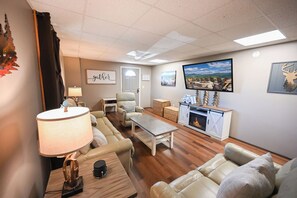 A living room with a fireplace, a television, and a sofa. - Bluff Mountain Vista • 4 Bed • 3 Bath • Stunning Views (Sevierville)