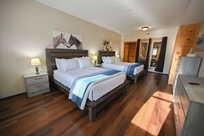 Quarto de hotel com duas camas, piso de madeira e obras de arte nas paredes.
