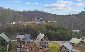 A residential area with multiple two-story houses, a prominent building on a hill, and a forested backdrop. - What a Wonderful World * 2 bed * 3 bath * sleeps 6 (Sevierville)