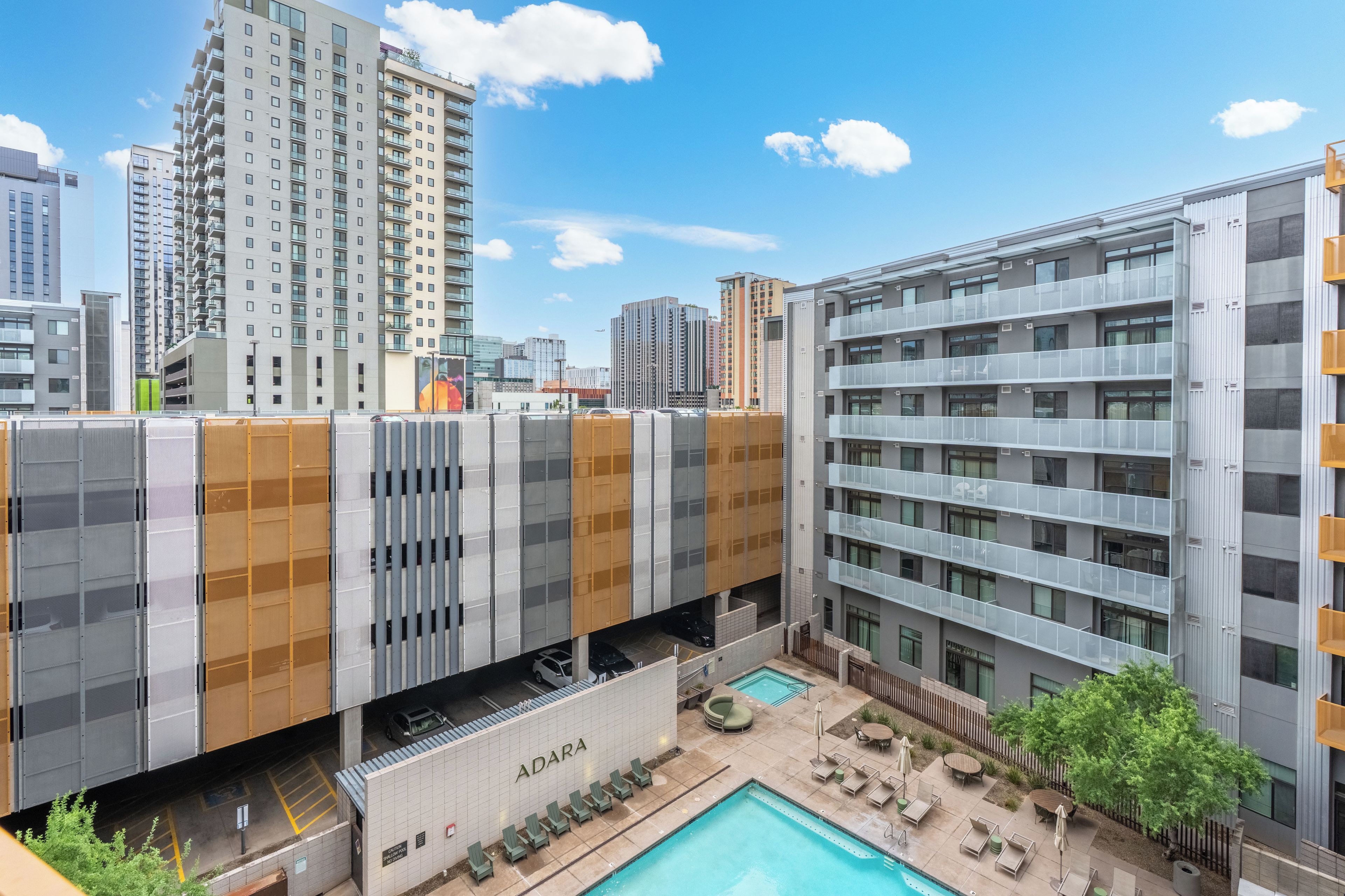 Un edificio moderno con un área de piscina en la azotea, que incluye sillas de descanso y una piscina.