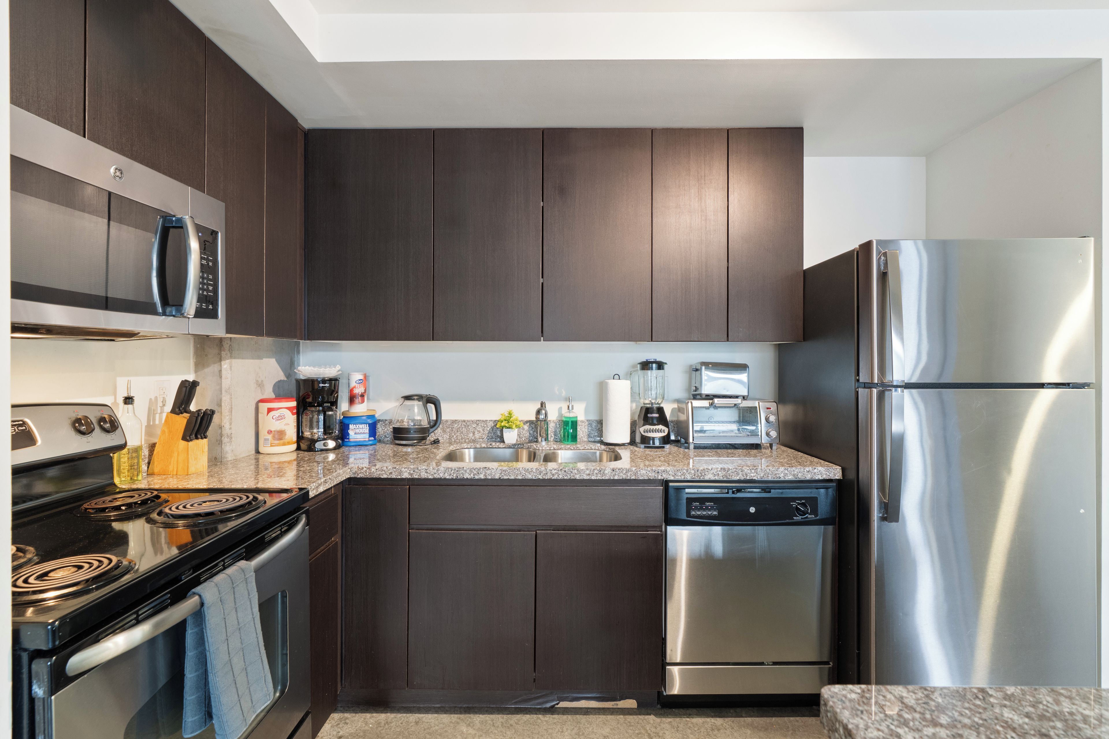 Una cocina moderna con gabinetes de madera oscura, electrodomésticos de acero inoxidable y encimeras de granito.