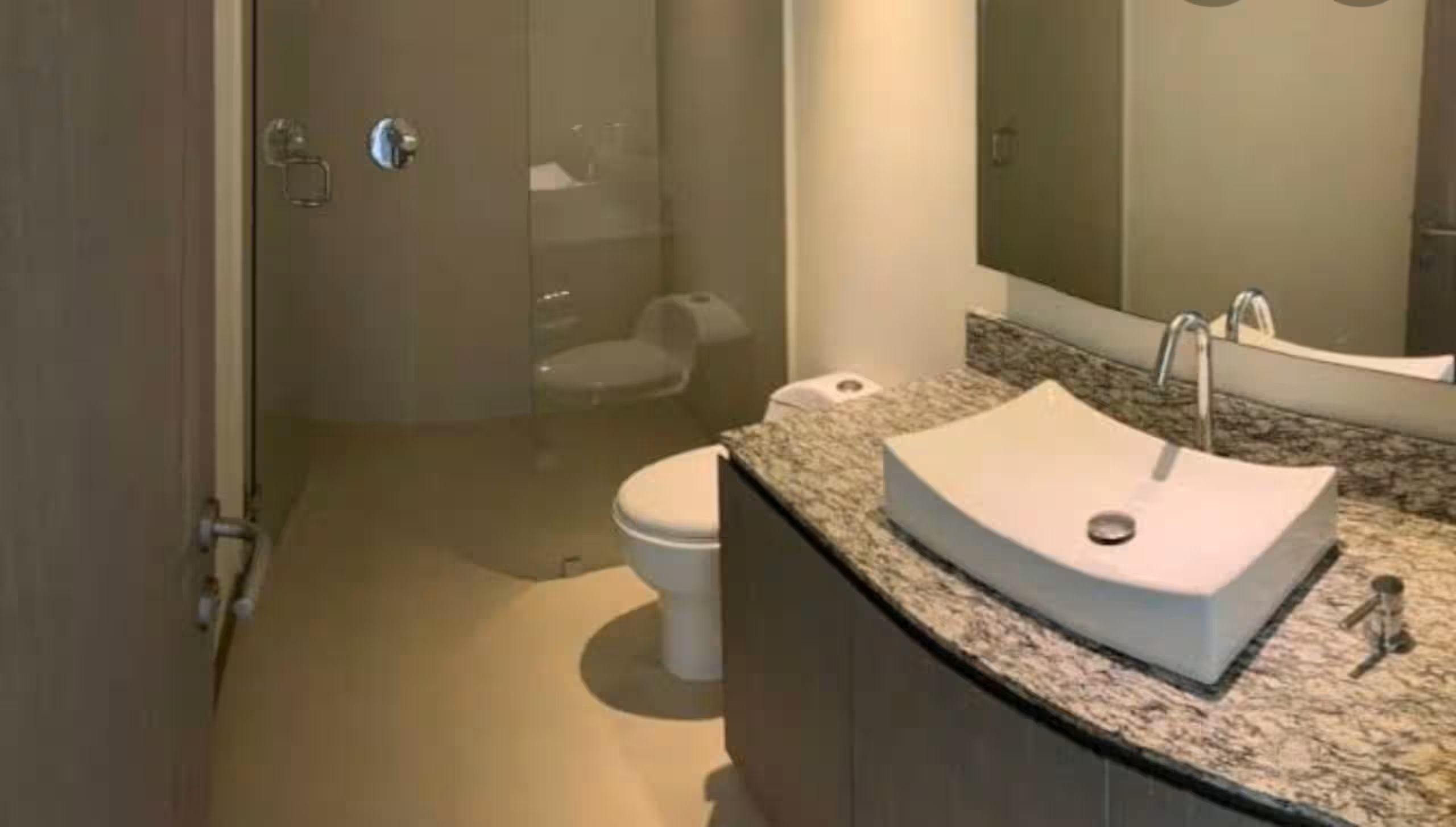 Un baño con inodoro, lavamanos y zona de ducha.