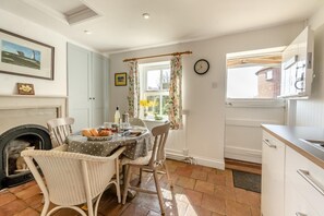 A cozy dining area with a fireplace, a dining table set for two, and a view of the outside. - 1 Bed in Snape (oc-sfmcs) (Snape)