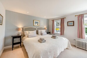 A bedroom with a large bed, bedside tables, a window with curtains, and a radiator. - 1 Bed in Snape (oc-sfmcs) (Snape)