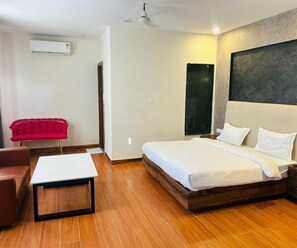 A modern hotel room with a bed, a desk, a chair, and a red couch. - Classic Red Chilly 3.O (Gorakhpur)