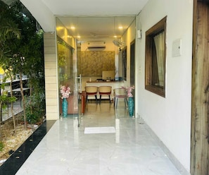 A modern interior with a glass door entrance, a dining area with chairs and a table, and a kitchen in the background. - Classic Red Chilly 3.O (Gorakhpur)