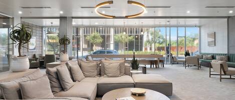 A modern interior with a sectional sofa, a round coffee table, and large windows offering a view of the outdoors.