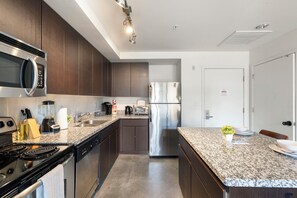 Eine moderne Küche mit Edelstahlgeräten, Granit-Arbeitsplatten und Holzschränken.