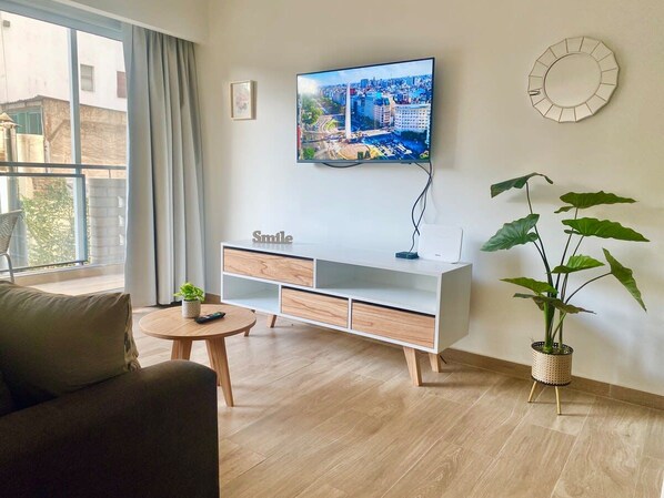 Moderni olohuone, jossa on litteänäyttöinen televisio, sohva, sohvapöytä, senkki ja ruukkukasvi.