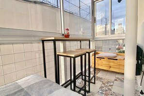 Et lille, moderne køkken med en træbordplade, en barstol og en potteplante.