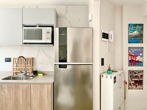 Eine kleine Küche mit Mikrowelle, Kühlschrank und Holzschränken.