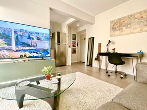 A modern living room with a flat-screen TV, a glass coffee table, a sofa, a desk with a chair, and a map on the wall. - 28- Incredible Oriental Style Apt. /Palermo Soho (Buenos Aires)