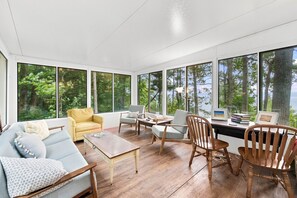 Una habitación amplia con un ventanal grande, un sofá, una mesa de centro y una silla de madera.