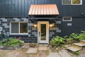 A modern house with a dark facade, a wooden front door, and two windows. - Stunning Crystal Lake Views | Private Hot Tub | Sleeps 10 | Near Beulah (Beulah)