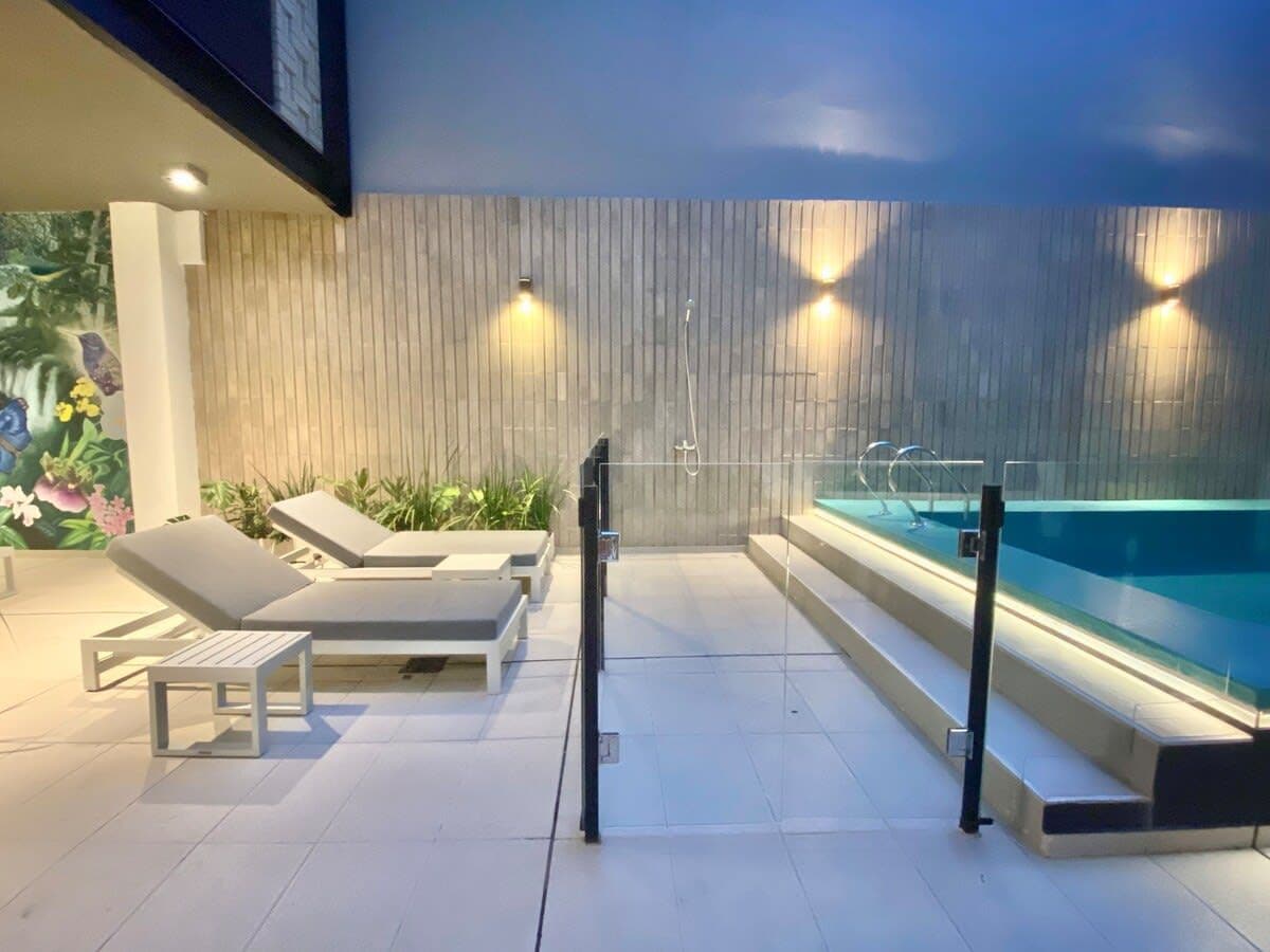 A pool area with lounge chairs and a hot tub.