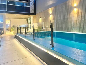 A swimming pool with a glass barrier, metal railings, and a tiled walkway. - 24- Modern Space in Palermo w/ Pool 2 Beds. (Buenos Aires)