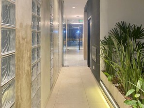 A corridor with glass block walls, a tiled floor, and a planter with green plants. - 24- Modern Space in Palermo w/ Pool 2 Beds. (Buenos Aires)