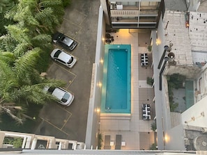 Eine Vogelperspektive eines Hotels mit Schwimmbecken, Parkplatz und einem Gebäude mit Balkonen.