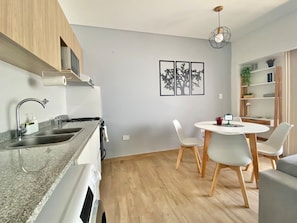 A modern kitchen with granite countertops, a built-in oven, and a dining area with a round table and white chairs. - 26- Modern Space in Palermo Soho w/Pool (Buenos Aires)