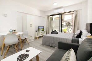 Ein modernes Hotelzimmer mit einem Bett, einem Schreibtisch, einem Stuhl, einer Couch und einem Balkon mit Aussicht.