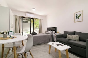 A modern, well-lit room with a bed, a sofa, a dining table with chairs, and a small white table. - 30- Modern Apt. w/ Great Amenities in Palermo (Buenos Aires)