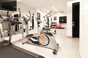 Ein moderner Fitnessraum mit Laufbändern, Hanteln und einer Spiegelwand.