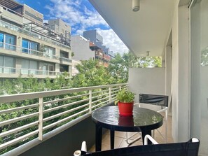 A balcony with a table and chairs, a potted plant, and a view of surrounding buildings. - 29- Unbeatable Apt w/Amenities on Terrace - Palermo (Buenos Aires)