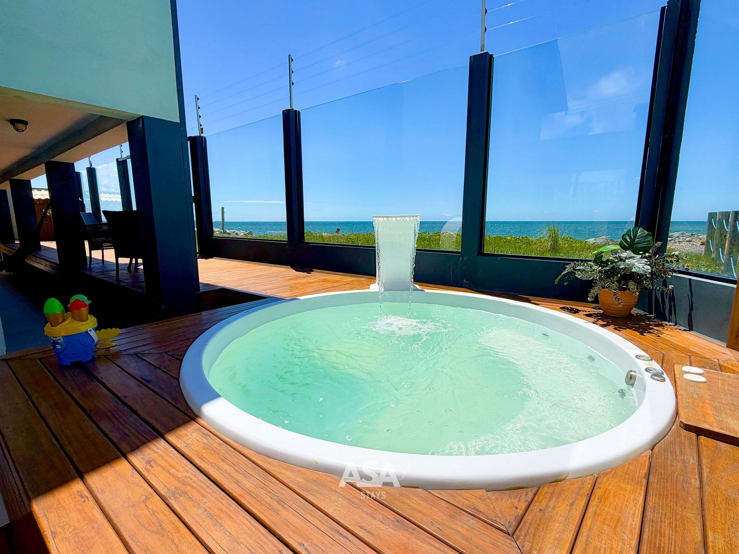 A hot tub on a wooden deck with a view of the ocean.