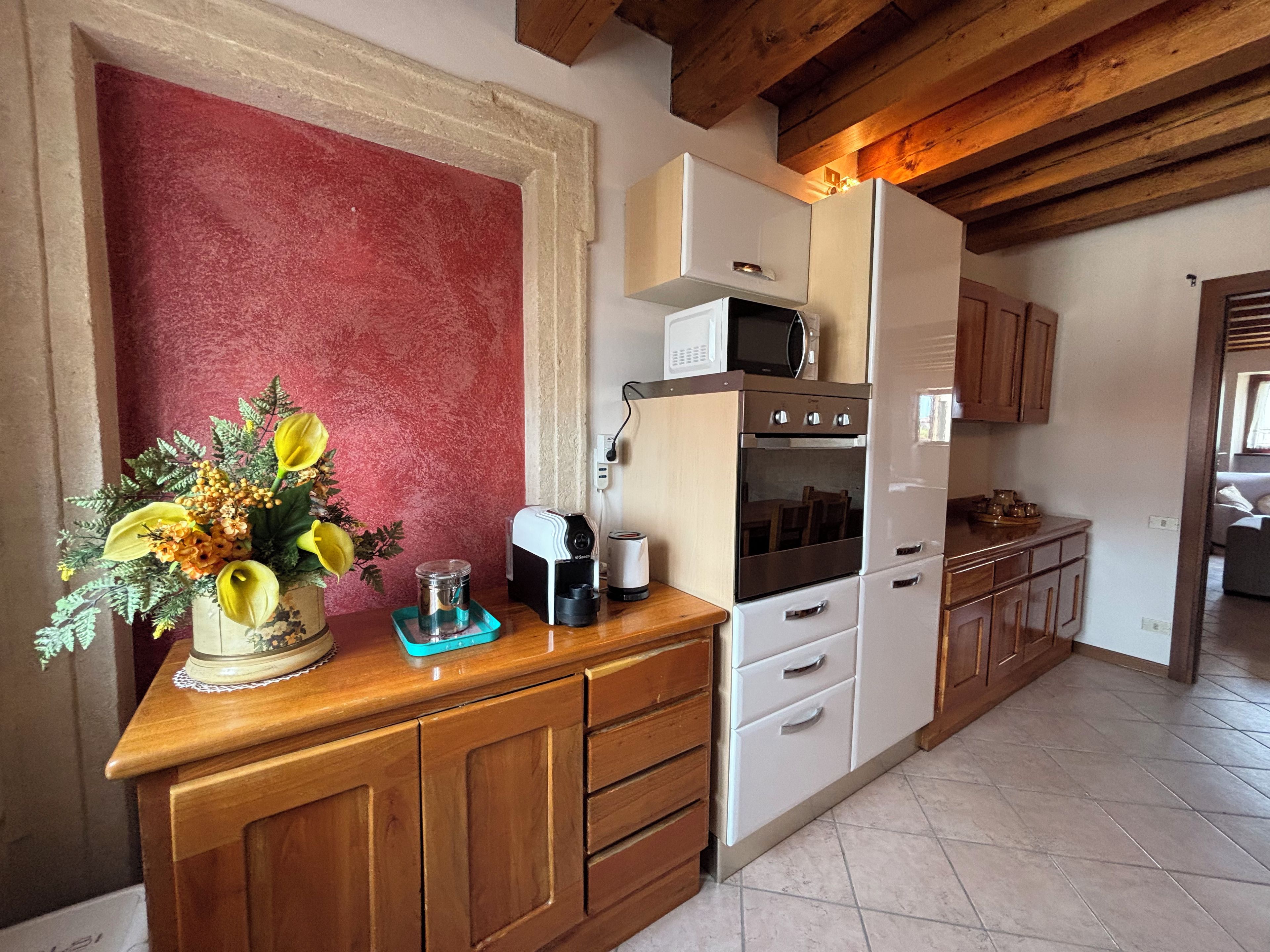 Una cocina con armarios de madera, un microondas, un horno y una cafetera.