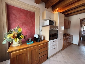 Una cocina con armarios de madera, un microondas, un horno y una cafetera.