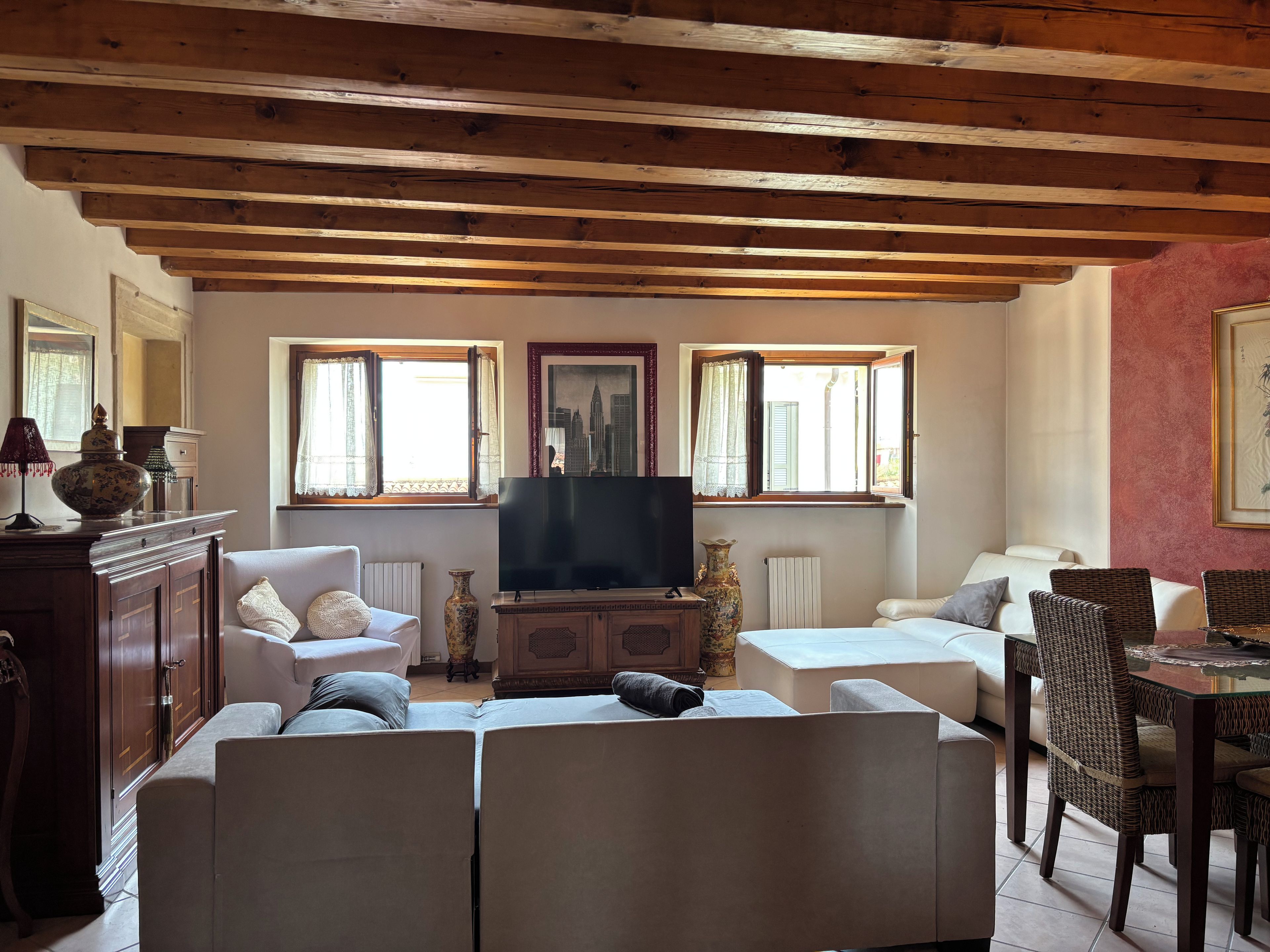 A living room with a sofa set, a television, and a dining area with wicker chairs.