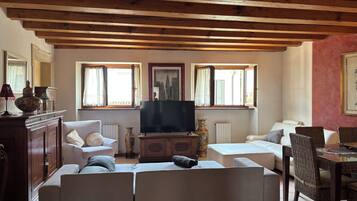 A living room with a sofa set, a television, and a dining area with wicker chairs.