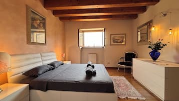 A bedroom with a bed, bedside tables, a dresser, a chair, a window, and wall-mounted lights.
