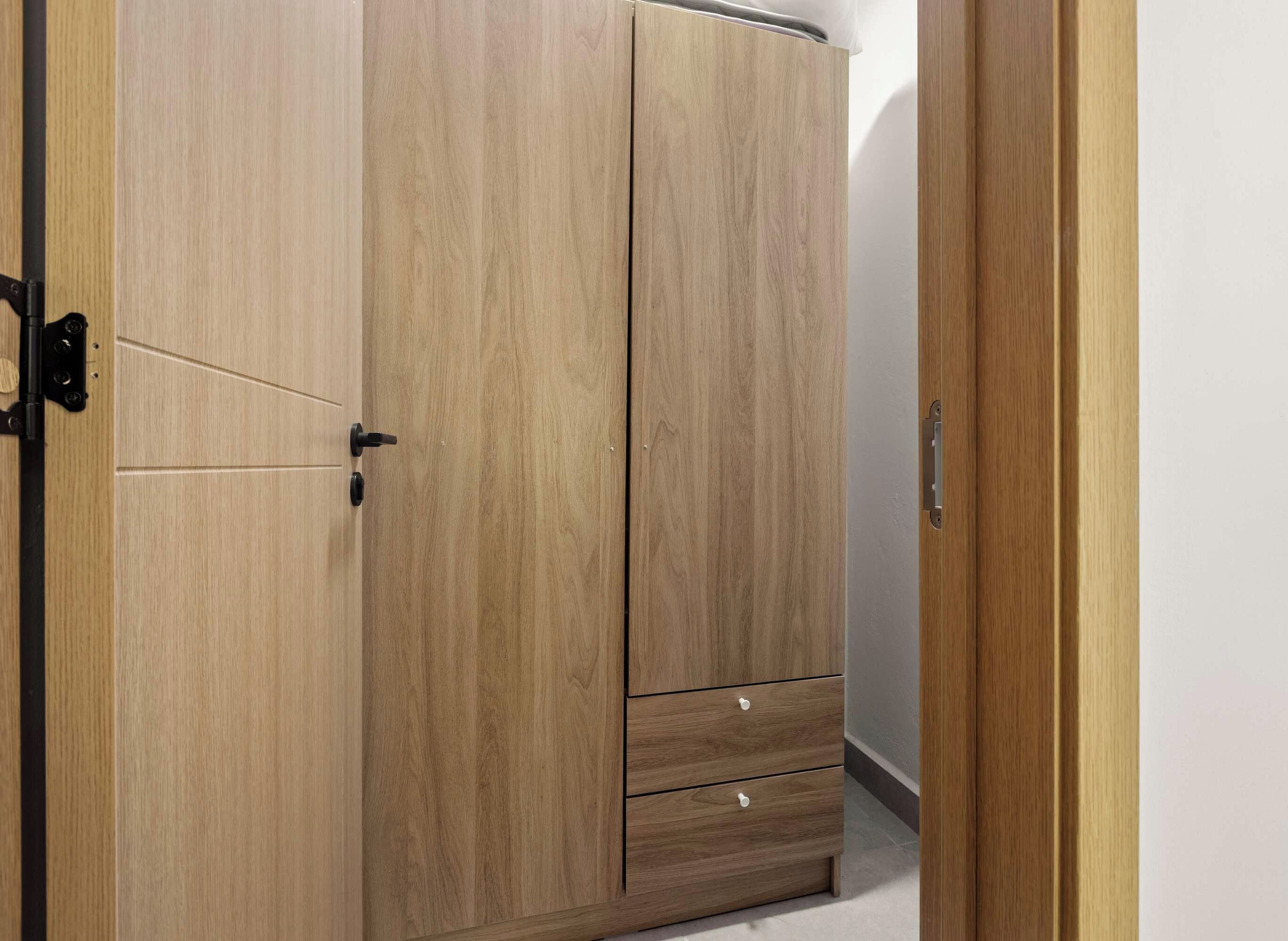 Ein hölzerner Kleiderschrank mit Schiebetür und einer kleinen Schublade.