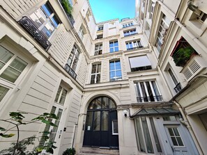 A multi-story building with a central entrance, large windows, and balconies with railings. - New Listing (Paris)