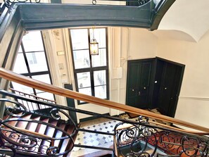 A staircase with ornate metal railings, a view of a door, and a hanging light fixture. - New Listing (Paris)