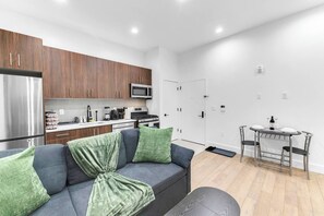 Eine moderne Küche mit Kühlschrank, Mikrowelle, Herd und Schränken. Es gibt eine Essecke mit Tisch und Stühlen.