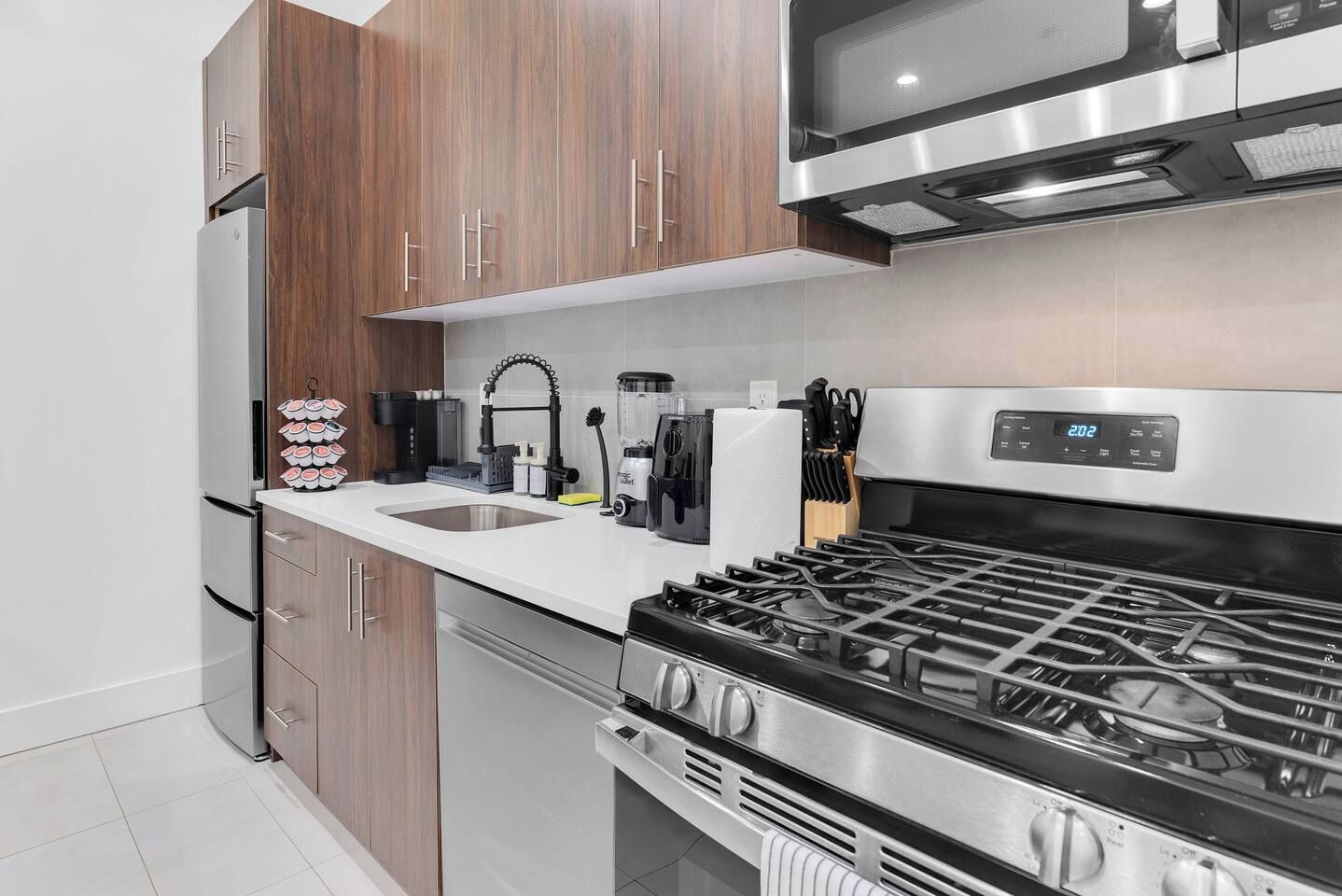 A modern kitchen with a stainless steel stove, wooden cabinets, a built-in microwave, and a sink.