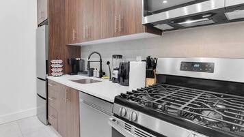 A modern kitchen with a stainless steel stove, wooden cabinets, a built-in microwave, and a sink.